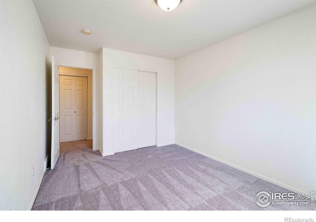 unfurnished bedroom featuring baseboards, carpet, and a closet