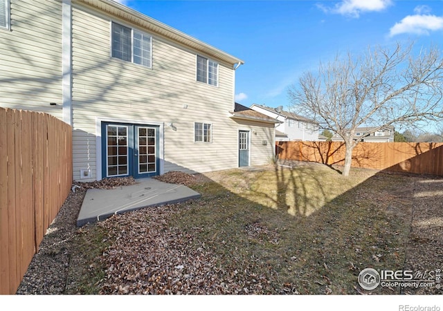 rear view of property featuring a fenced backyard and french doors