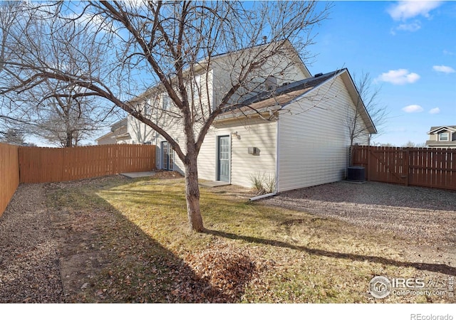 exterior space with central air condition unit, a lawn, a gate, and a fenced backyard