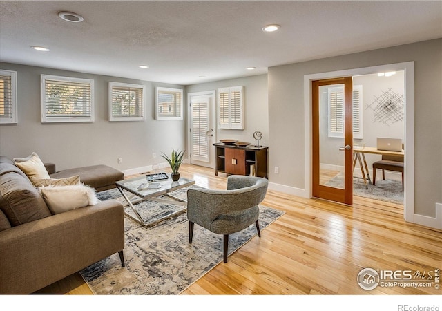 living area with light wood-type flooring, recessed lighting, and baseboards