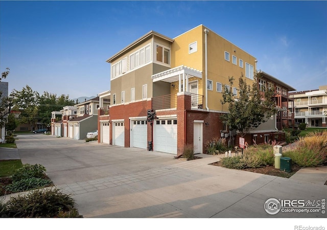 exterior space featuring brick siding, an attached garage, driveway, and stucco siding