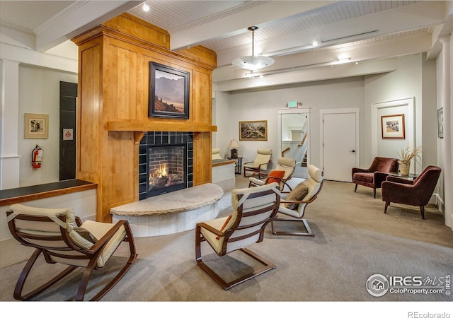 carpeted living room featuring beamed ceiling and a tiled fireplace