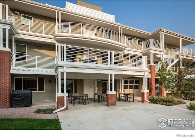 exterior space featuring a patio, outdoor dining area, a balcony, and stucco siding