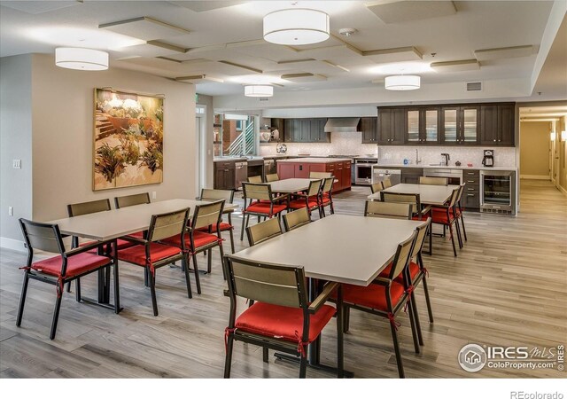 dining room with beverage cooler, light wood finished floors, baseboards, and visible vents
