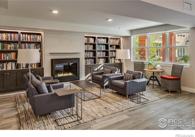 sitting room featuring visible vents, a large fireplace, wood finished floors, baseboards, and recessed lighting