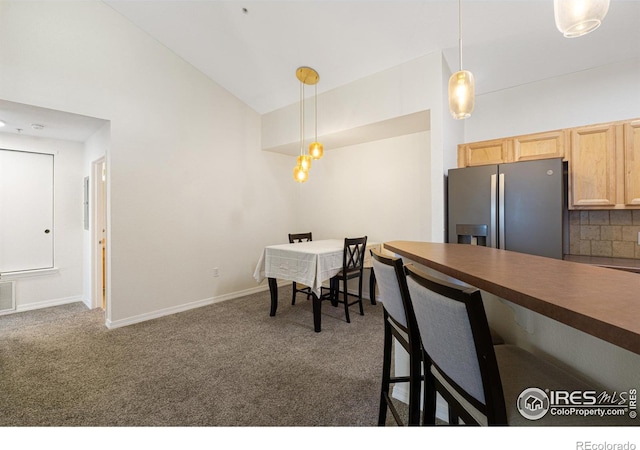 dining area with lofted ceiling, dark carpet, baseboards, and visible vents