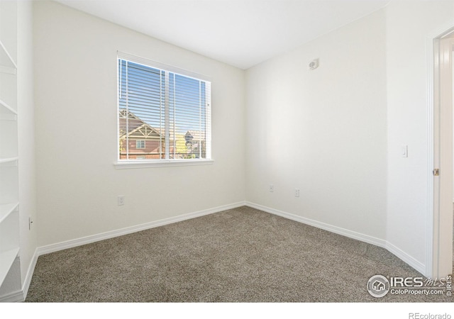 carpeted spare room featuring baseboards