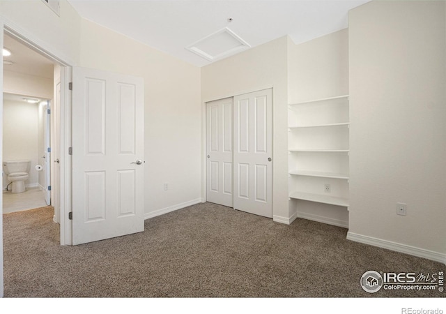 unfurnished bedroom with attic access, carpet floors, a closet, and baseboards
