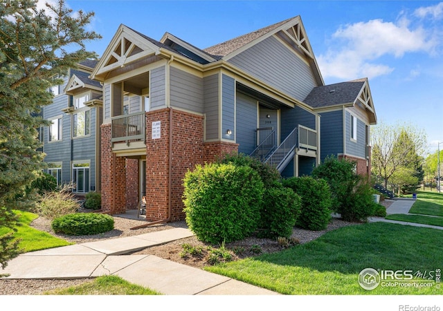 view of front of home featuring brick siding, stairway, and a front yard
