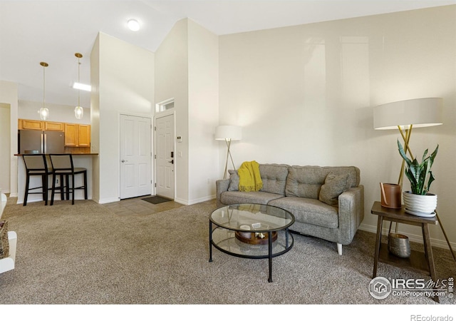 carpeted living area with baseboards and high vaulted ceiling