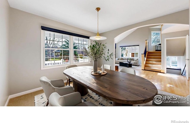 dining space featuring baseboards, arched walkways, and stairway