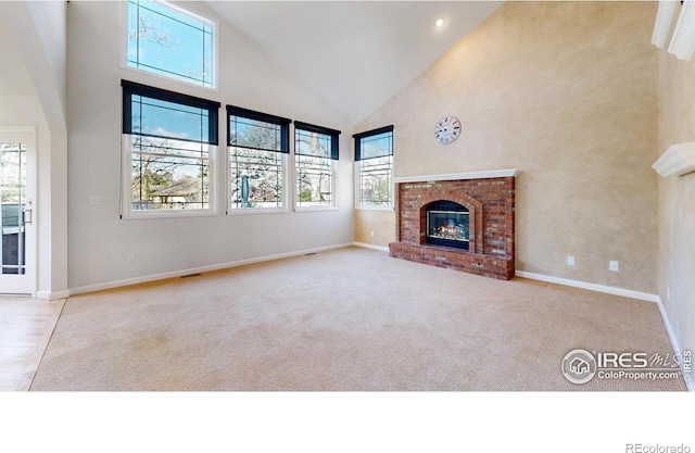 unfurnished living room with baseboards, carpet, a fireplace, and high vaulted ceiling