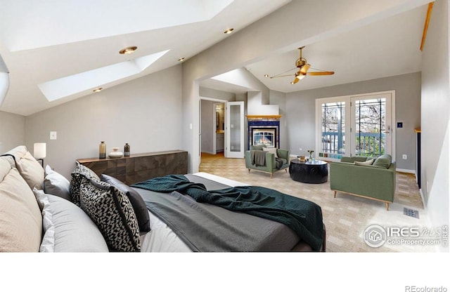 carpeted bedroom with a glass covered fireplace and lofted ceiling with skylight