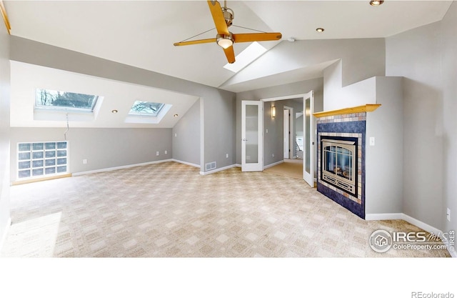 unfurnished living room with carpet flooring, baseboards, and vaulted ceiling with skylight