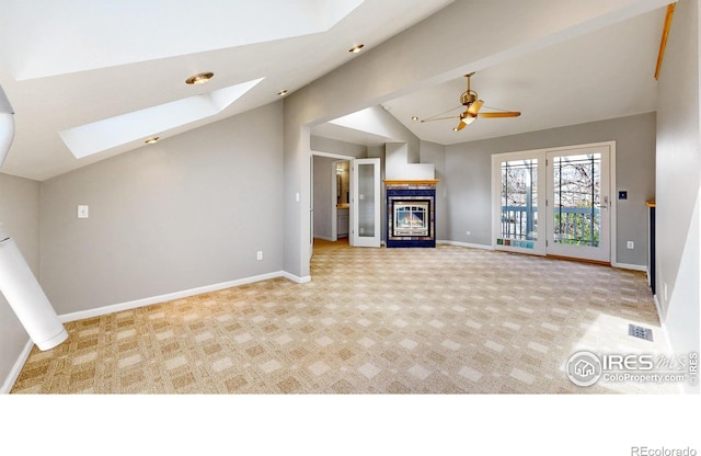 unfurnished living room with baseboards, carpet, a glass covered fireplace, and lofted ceiling with skylight