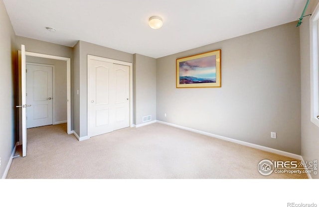 unfurnished bedroom featuring carpet flooring, baseboards, visible vents, and a closet