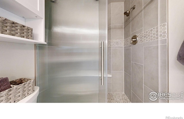 bathroom featuring toilet and a shower stall