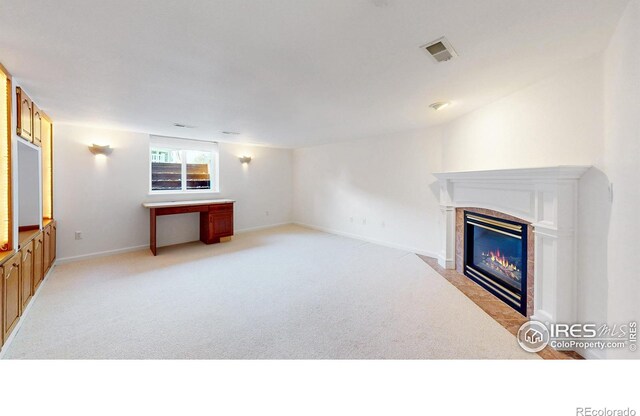 unfurnished living room with light colored carpet, baseboards, visible vents, and a tile fireplace