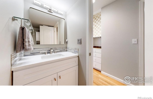 bathroom with vanity, baseboards, backsplash, and wood finished floors