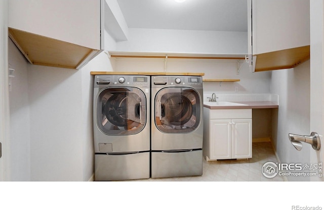 washroom with washing machine and clothes dryer, light floors, a sink, and cabinet space