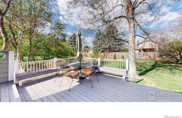deck with outdoor dining area, fence, and a yard