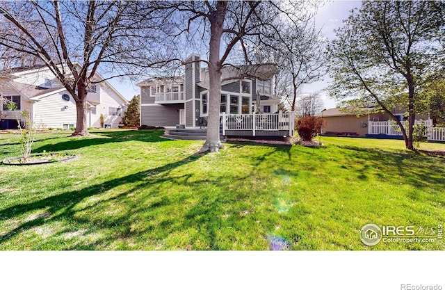 rear view of house featuring a chimney, a yard, and a deck