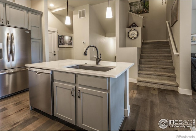 kitchen featuring visible vents, dark wood-style flooring, gray cabinets, a sink, and stainless steel appliances