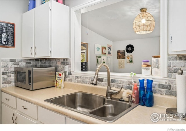 1208 Briarwood Rd, Fort Collins, CO 80521 - kitchen with a sink, stainless steel microwave, backsplash, light countertops, and white cabinets