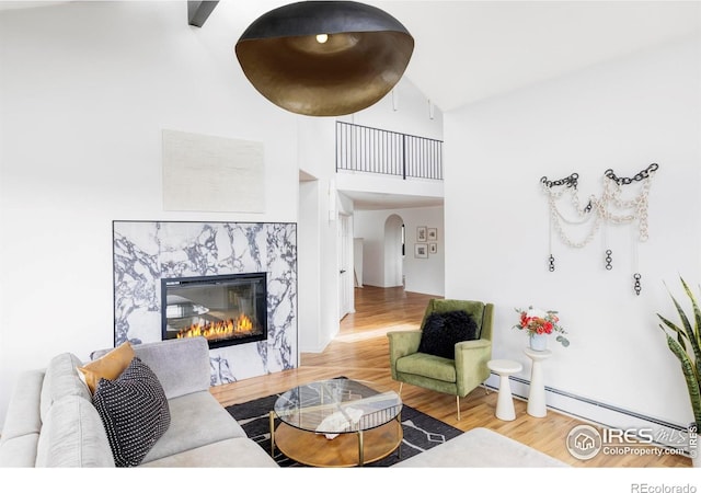 319 S Peak Rd, Boulder, CO 80302 - living area with arched walkways, wood finished floors, a baseboard heating unit, a high ceiling, and a premium fireplace