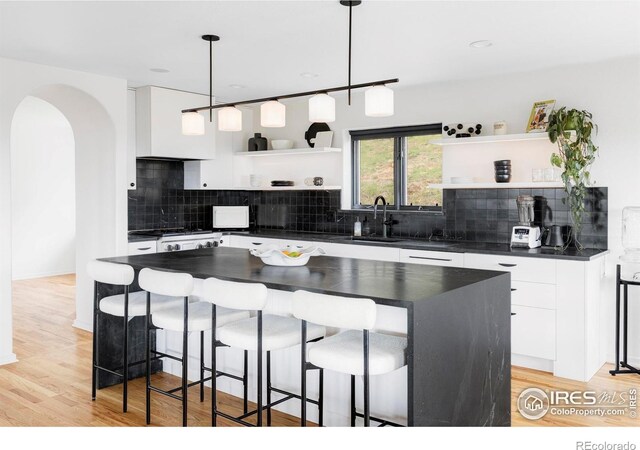 319 S Peak Rd, Boulder, CO 80302 - kitchen featuring open shelves, dark countertops, a breakfast bar area, white cabinets, and a sink