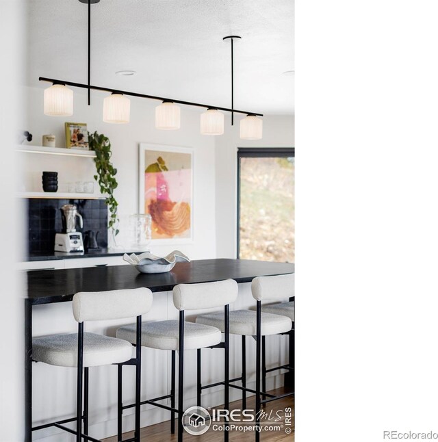 319 S Peak Rd, Boulder, CO 80302 - kitchen with open shelves, pendant lighting, wood finished floors, and a kitchen bar