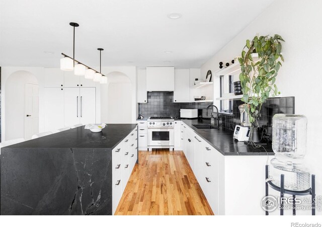 319 S Peak Rd, Boulder, CO 80302 - kitchen with dark countertops, open shelves, high end stainless steel range, a sink, and arched walkways