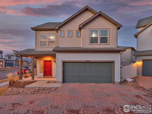 traditional home featuring fence, an attached garage, and decorative driveway