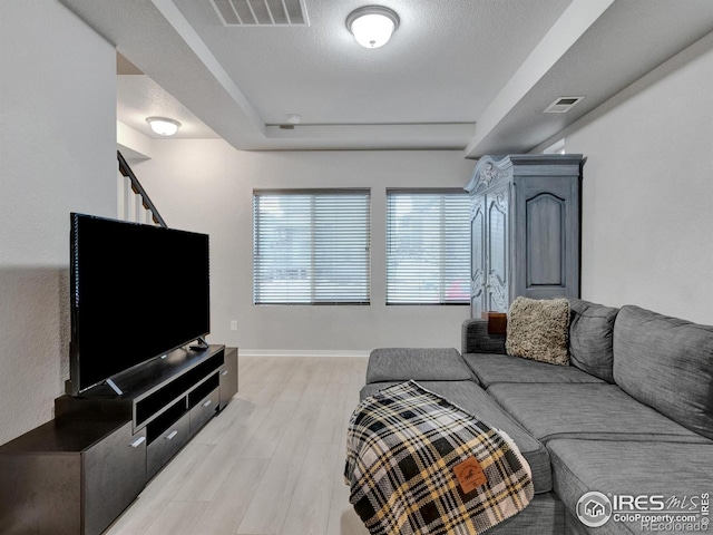 living room featuring visible vents, baseboards, stairway, and light wood-type flooring