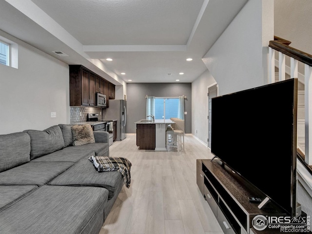 living room with visible vents, recessed lighting, light wood finished floors, and a wealth of natural light