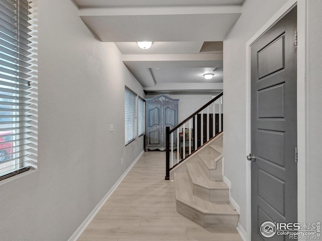 hallway with baseboards, stairs, and a wealth of natural light