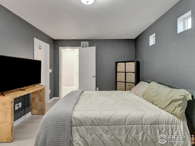 bedroom featuring a textured wall, wood finished floors, and visible vents