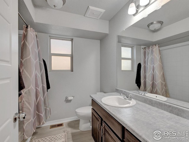 full bath with vanity, toilet, baseboards, wood finished floors, and visible vents