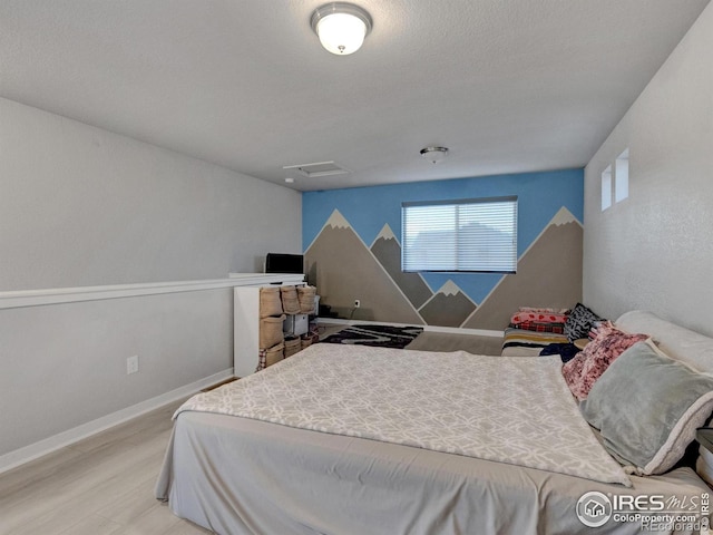 bedroom with baseboards, attic access, and light wood-type flooring