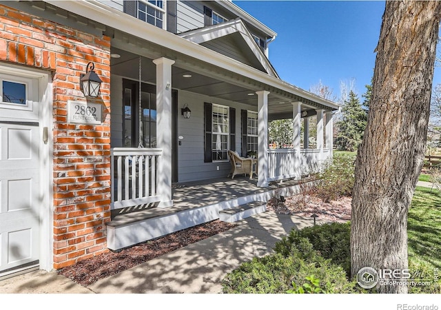 property entrance with a porch and brick siding