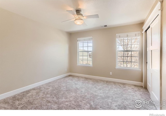 unfurnished bedroom with ceiling fan, visible vents, light colored carpet, baseboards, and a closet