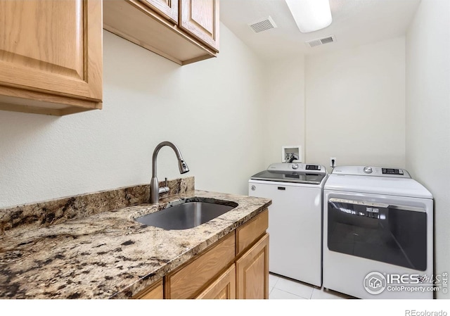 washroom with visible vents, a sink, cabinet space, and washer and dryer