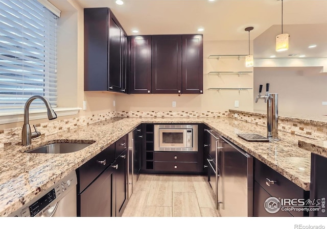 kitchen with hanging light fixtures, appliances with stainless steel finishes, a sink, light stone counters, and recessed lighting