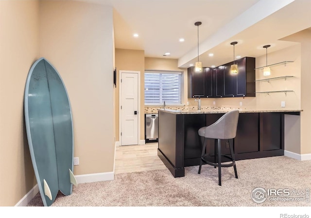 kitchen featuring a kitchen breakfast bar, stainless steel dishwasher, baseboards, a peninsula, and light carpet