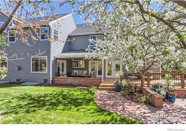 back of house with a lawn, a shingled roof, and french doors