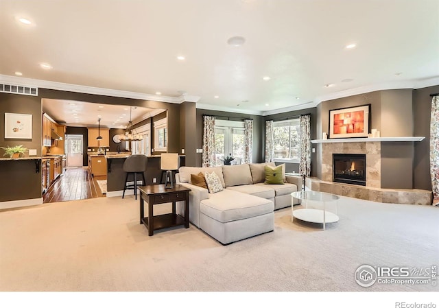 living area featuring visible vents, baseboards, ornamental molding, recessed lighting, and a premium fireplace