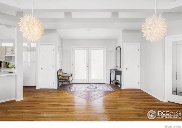 foyer entrance with wood finished floors, a chandelier, baseboards, and healthy amount of natural light