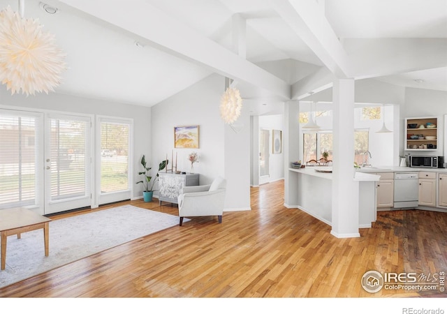 kitchen with open floor plan, light wood finished floors, white dishwasher, light countertops, and a sink