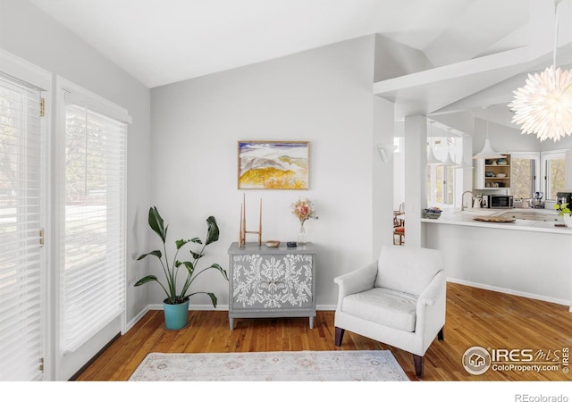 sitting room with wood finished floors, vaulted ceiling, and baseboards