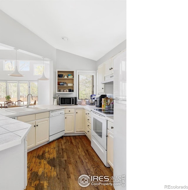 kitchen with white appliances, vaulted ceiling, under cabinet range hood, dark wood-type flooring, and a sink